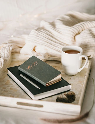 a photograph of a desk with a journal on top and a cup of coffee