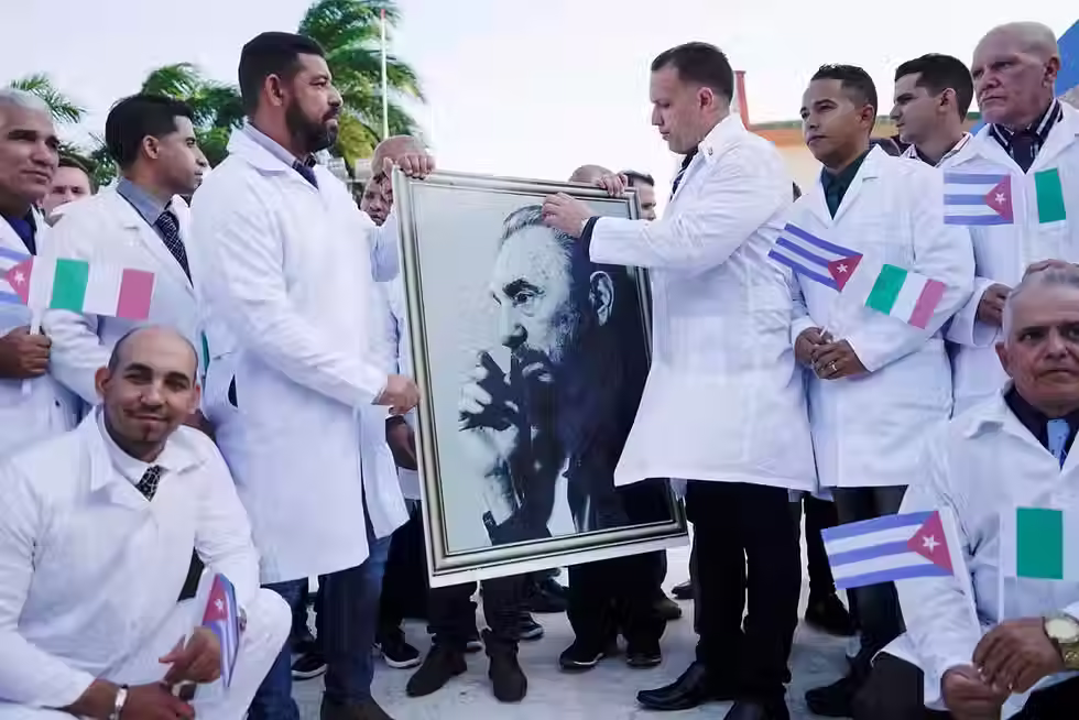 Médicos cubanos seguram uma imagem do falecido presidente cubano Fidel Castro durante uma cerimônia de despedida antes de partir para a Itália para tratar vítimas do coronavírus. Havana, Cuba, em 21 de março de 2020.
