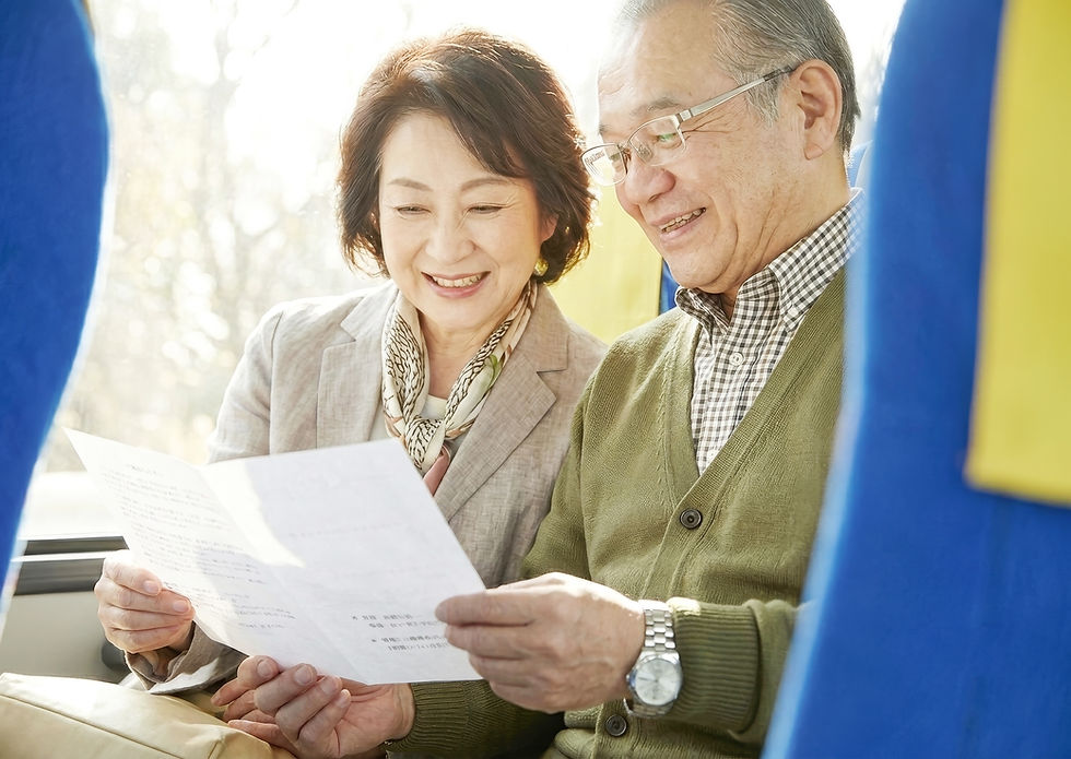 山口市での貸切バス旅行中に車内でパンフレットを笑顔で眺めるシニア夫婦