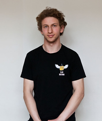 Personal trainer standing in a balck T shirt with hands clasped.