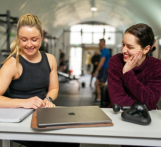 Personal trainer with a female client and a laptop on the desk going over a proposed training plan.