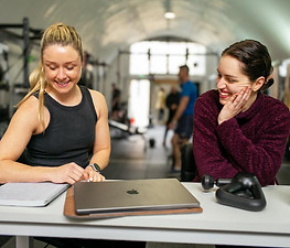 Personal trainer with a female client and a laptop on the desk going over a proposed training plan.