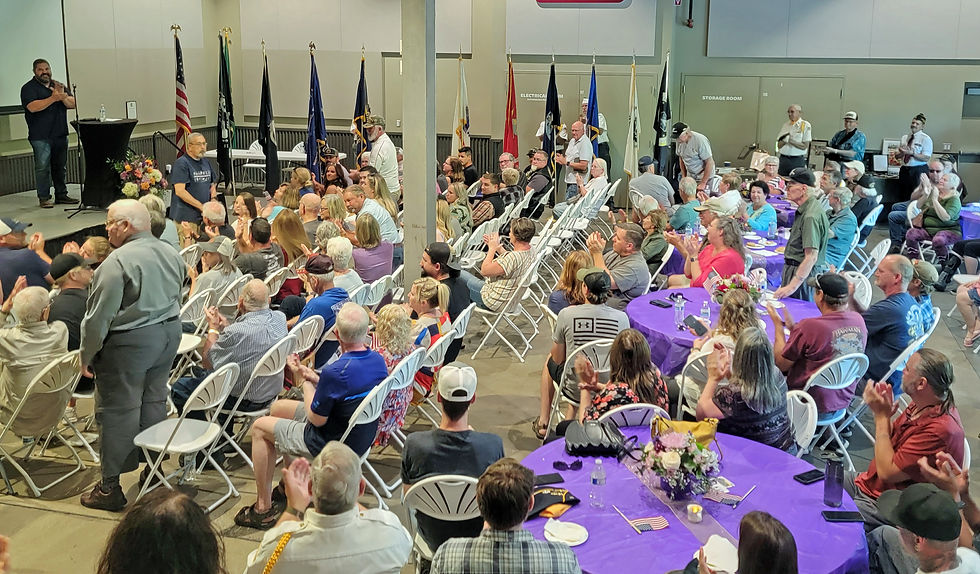 Last year’s event emcee, Tony Sandoval of the Washington State Department of Veterans Affairs, far left, asks the Purple Heart recipients in the room to stand during the 2024 ceremony, held at the Pybus Public Market.