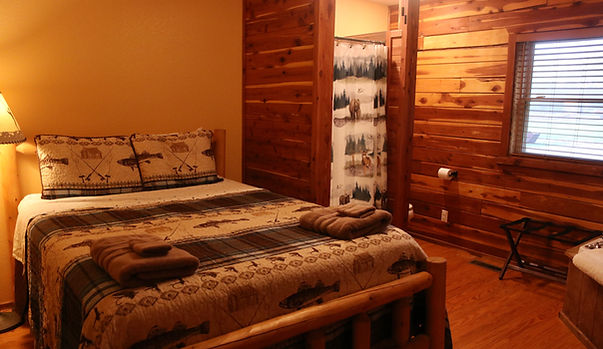 A cozy log cabin-style guest room with a bed, wooden furniture, and rustic decor.