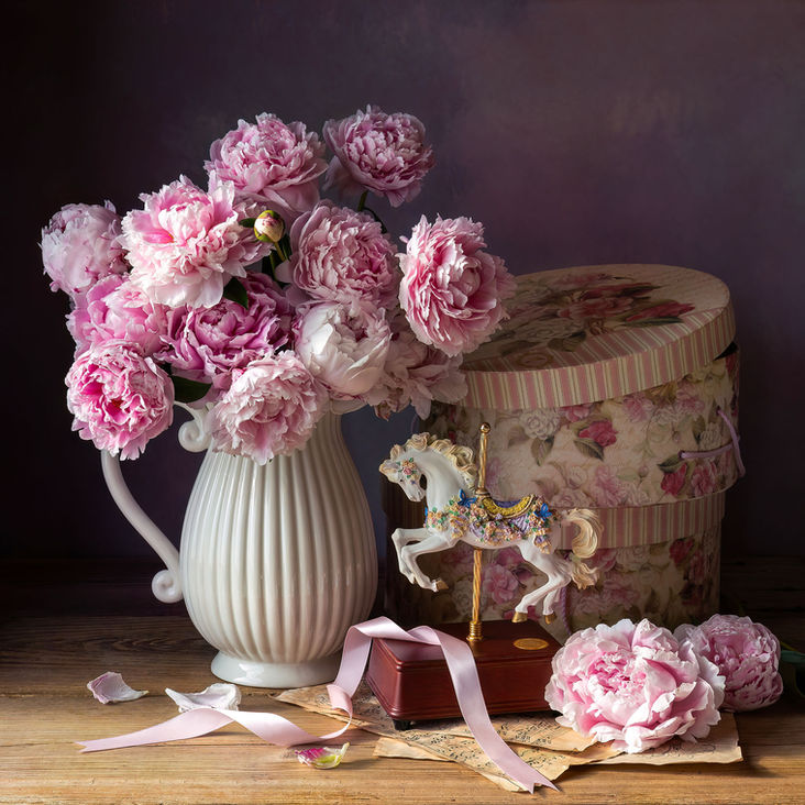 Immerse yourself in the timeless elegance of our "Peonies and Music Box" fine art photography. This piece imbued with a feminine vibe, was lovingly created around the Mother's Day celebration, exuding a gentle and sweet feel. Featuring beautiful pink fresh-cut peonies from the garden, complemented by a White Horse vintage musical box and retro hat round boxes, it evokes memories of eras when women adorned Derby Day hats. Perfect for adding a touch of nostalgic charm to any space, this artwork encapsulates the delicate beauty and cherished traditions of the past. Discover the subtle sophistication and exquisite details that make this piece a treasured addition to your fine art collection.