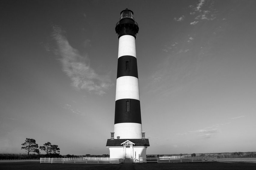 Bodie Island Lighthouse standing tall on North Carolina’s Outer Banks, centered against a flat coastal landscape under open sky.