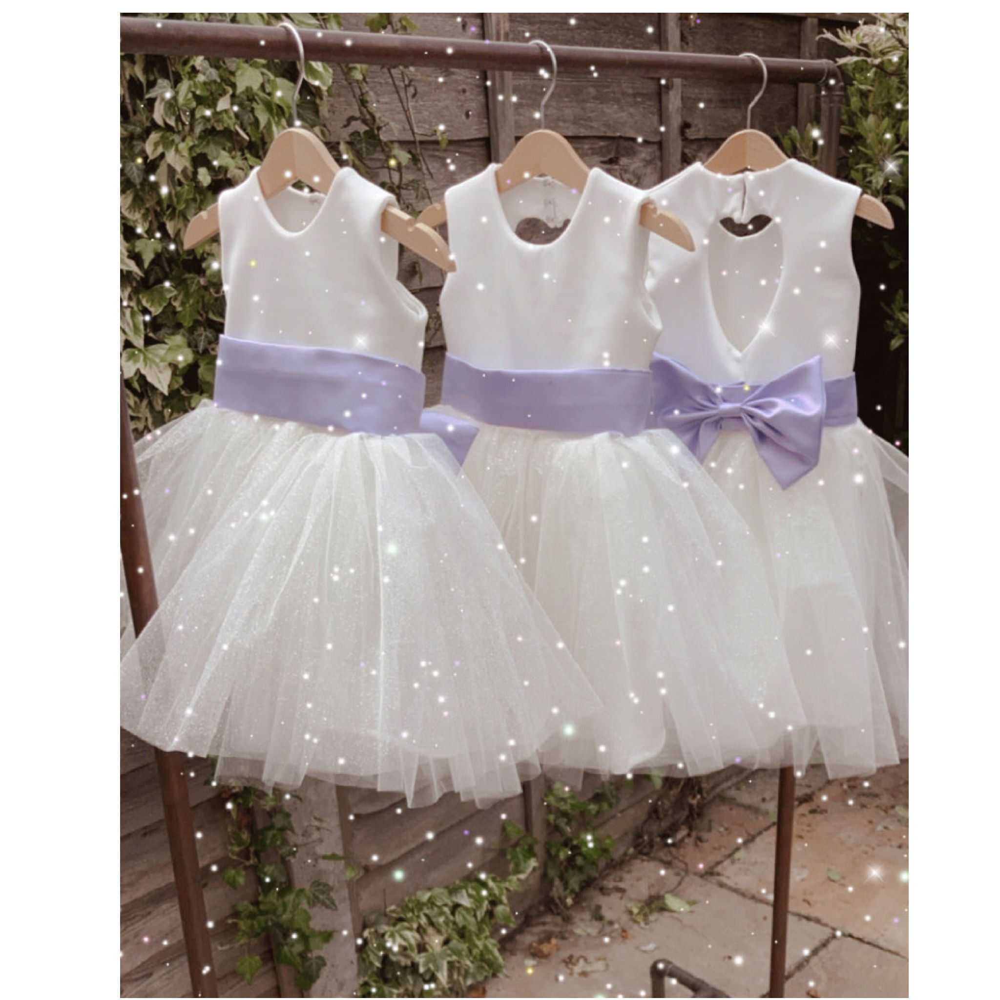 A handmade ivory white tutu dress with a heart cut out back. It features a sparkly tulle skirt that falls knee length, and has a large duchess satin bow sash. The perfect flower girl, birthday dress or Christmas party dress