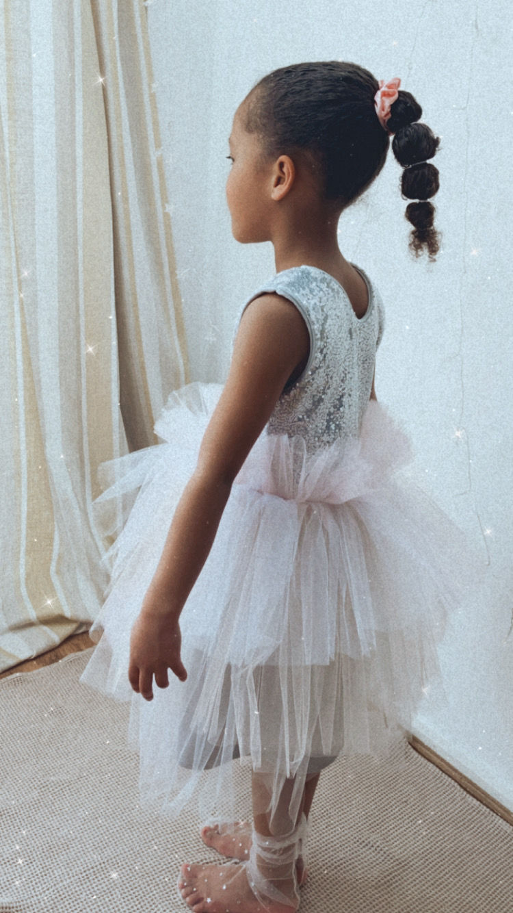 A handmade sequin tutu dress with a silver sequin top and a pastel rainbow tutu skirt that falls just below the knee. The perfect flower girl, birthday dress or Christmas party dress