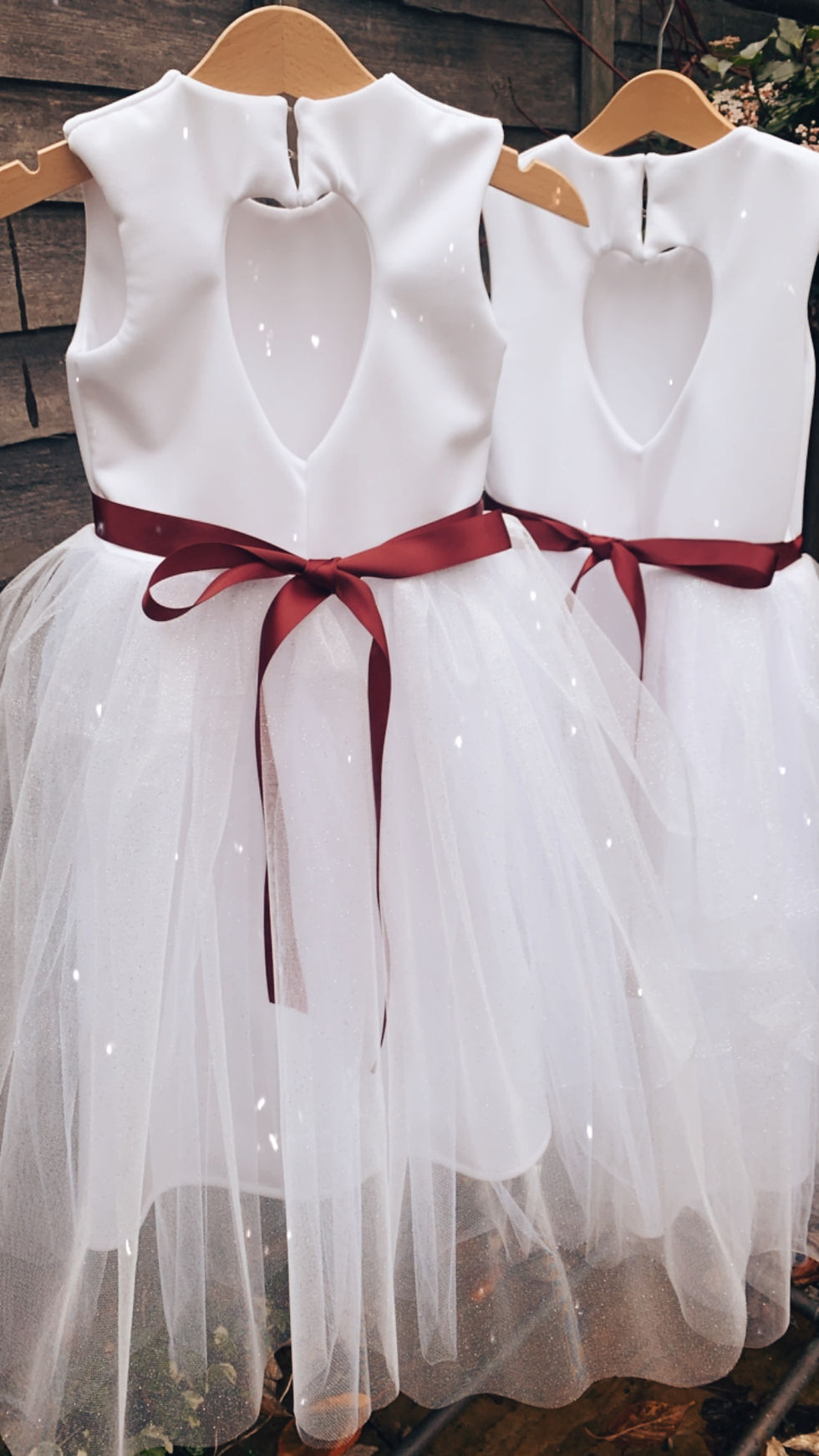 Thumbnail: A handmade ivory white dress with a heart cut out back. It features a sparkly tulle skirt that falls ankle length, and a soft wine ribbon bow sash. The perfect flower girl, birthday dress or Christmas party dress