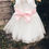 Thumbnail: A handmade ivory white tutu dress with a heart cut out back. It features a sparkly tulle skirt that falls knee length, and has a large duchess satin bow sash. The perfect flower girl, birthday dress or Christmas party dress