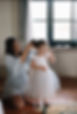 a little flower girl getting ready wearing a handmade flower girl dress with an embroidered top soft tulle skirt and cute tulle frill sleeves