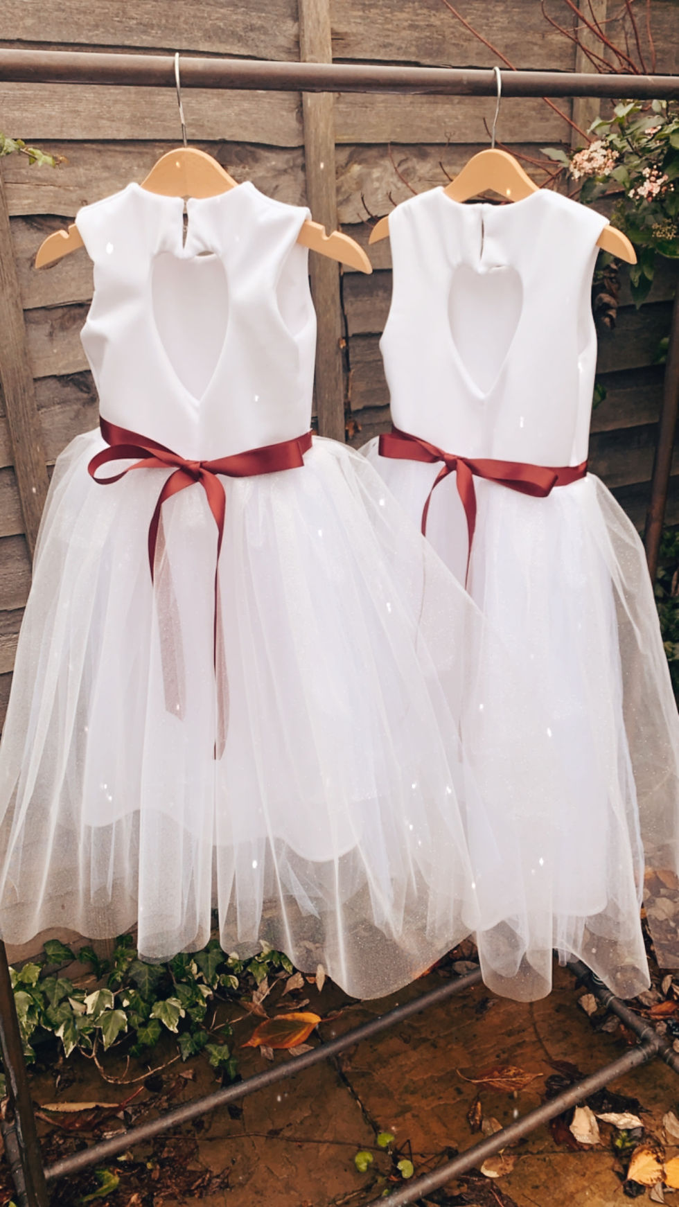 A handmade ivory white dress with a heart cut out back. It features a sparkly tulle skirt that falls ankle length, and a soft wine ribbon bow sash. The perfect flower girl, birthday dress or Christmas party dress