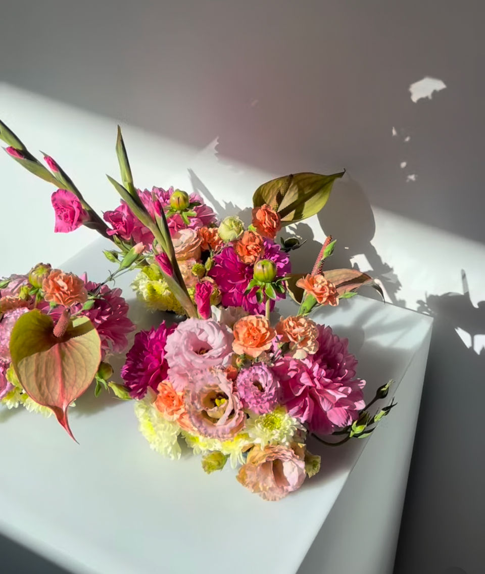 Whimsical and feminine table arrangement corporate flowers for long lunch at Victoria Park, Herston, Brisbane, featuring sunset pink, yellow and orange flowers