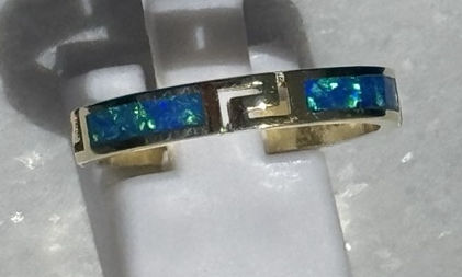Close‑up of gold ring featuring Greek key pattern and shimmering blue opal, highlighting its elegant design and fine details