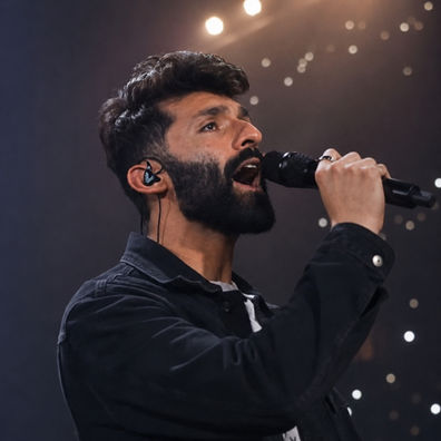 Andrew Meraldson singing a powerful note into a handheld microphone during a live performance.