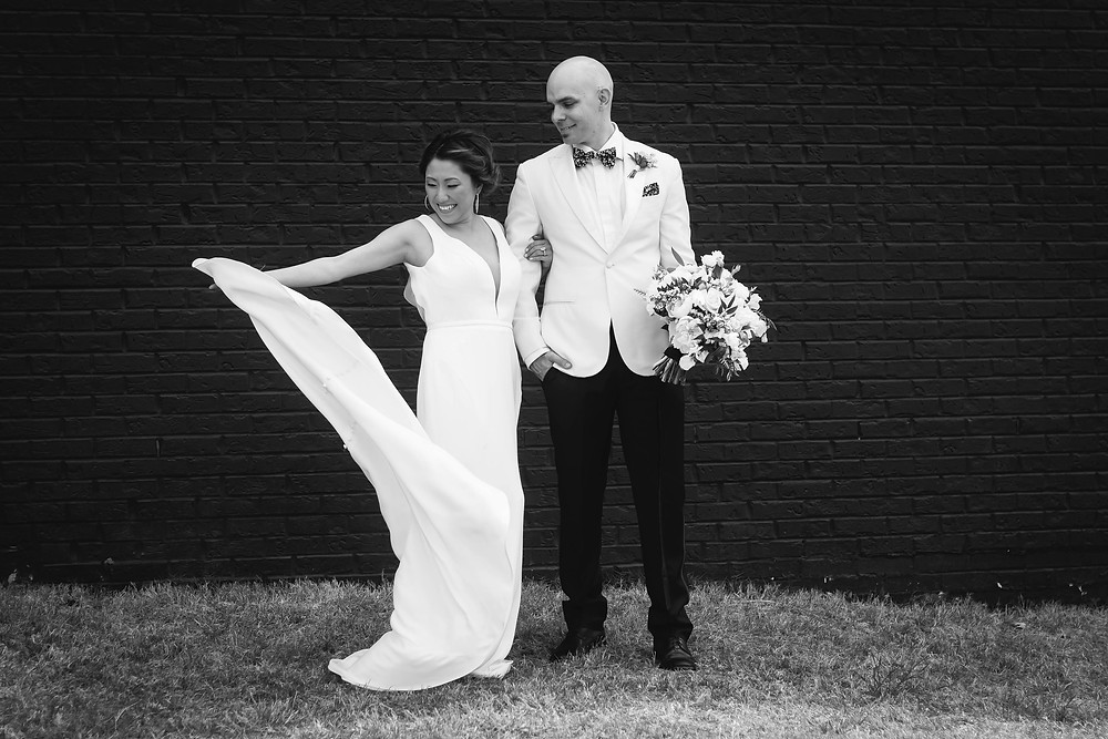 Black and white bride and groom play with wedding dress in wind at Noah Liff Opera Center