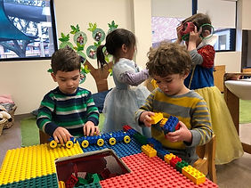 2 boys playing with legos and 2 girls playing dress up
