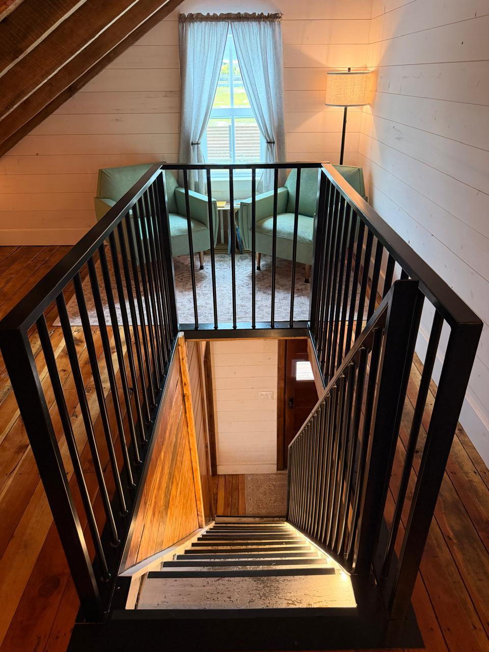 Die Treppe verbindet Erdgeschoss und Dachgeschoss. Alte Holzelemente und moderne Sicherheitsgeländer zeigen die Verbindung von Geschichte und heutiger Nutzung.