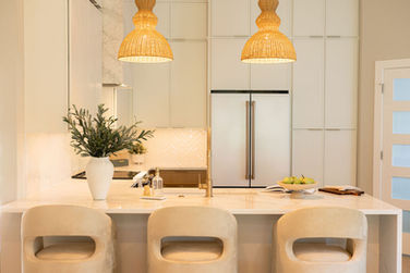 Jacksonville Beach kitchen renovation with white cabinetry, waterfall island, woven pendant lights, brass fixtures, and curved counter stools