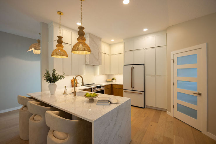 After photo of a Jacksonville Beach kitchen remodel by Zen Reno & Design, featuring warm wood and white cabinetry, quartz countertops, waterfall peninsula, woven pendant lighting, and layered neutral finishes.