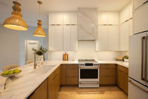 Custom kitchen remodel in Jacksonville Beach, Florida by Zen Reno & Design, featuring warm wood cabinetry, white upper cabinets, quartz countertops, and woven pendant lighting.