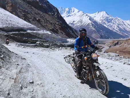 Woman riding a motorcycle on a high-altitude mountain road at Kunzum La in the Indian Himalayas.