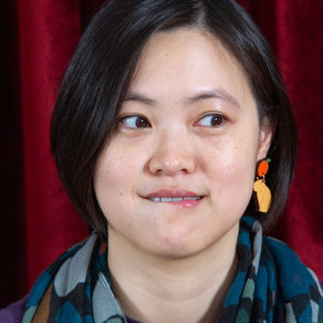 An Asian woman in a purple long sleeve top and patterned scarf. It is a portrait photograph by HeardinLondon