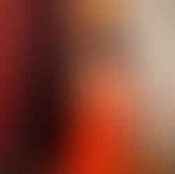 A black woman holds orange some orange flowing fabric and stands in front of  some brown fabric during a maternity photoshoot by pregnancy photographer HeardinLondon