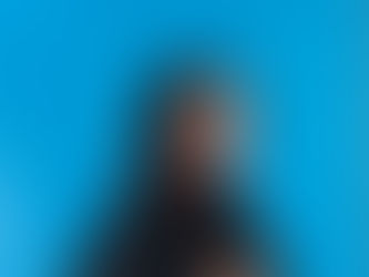 A caucasian woman with long brown hair stands in front of a blue backdrop. It is an empowerment photograph taken by confidence photographer HeardinLondon