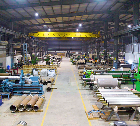 Industrial steel casting manufacturing facility with workers, machinery, and metal pipes in production.