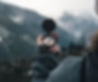Man sieht eine verschwommene Bergkulisse im Hintergrund und davor eine Hand, die einen Kompass in der Hand hält.