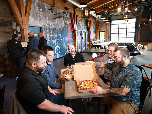 Group of men sitting at a restaurant table, eating pizza.