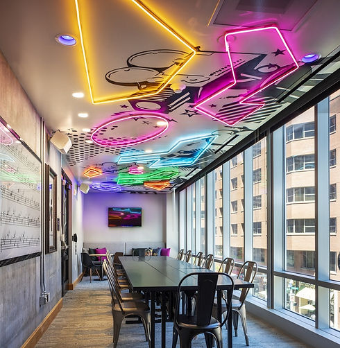 Trendy restaurant function room with tables, chairs, large windows, and geometric neon lights on the ceiling