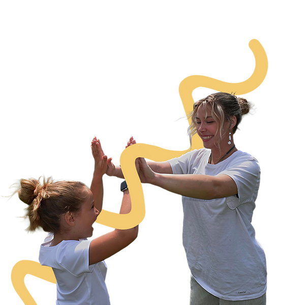 Gabrielle souriant et tapant des mains avec un enfant lors d’une activité d’apprentissage.