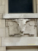 Intricately stone carved skull with horns underneath a partial window.