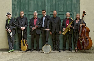 Die Musiker der Barrelhouse Jazzband posieren für ein Bandfoto vor einem grünen Tor.