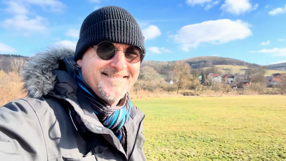 Jan Luley wearing a winter jacket and hat, standing in a hilly landscape in Eastern Hesse with nature in the background.