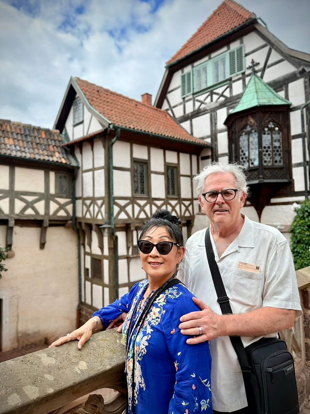 A couple poses in front of a half-timbered building.