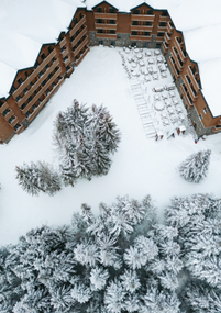 Aerial view of a snow-covered Swissotel Kolasin near pine trees and snow