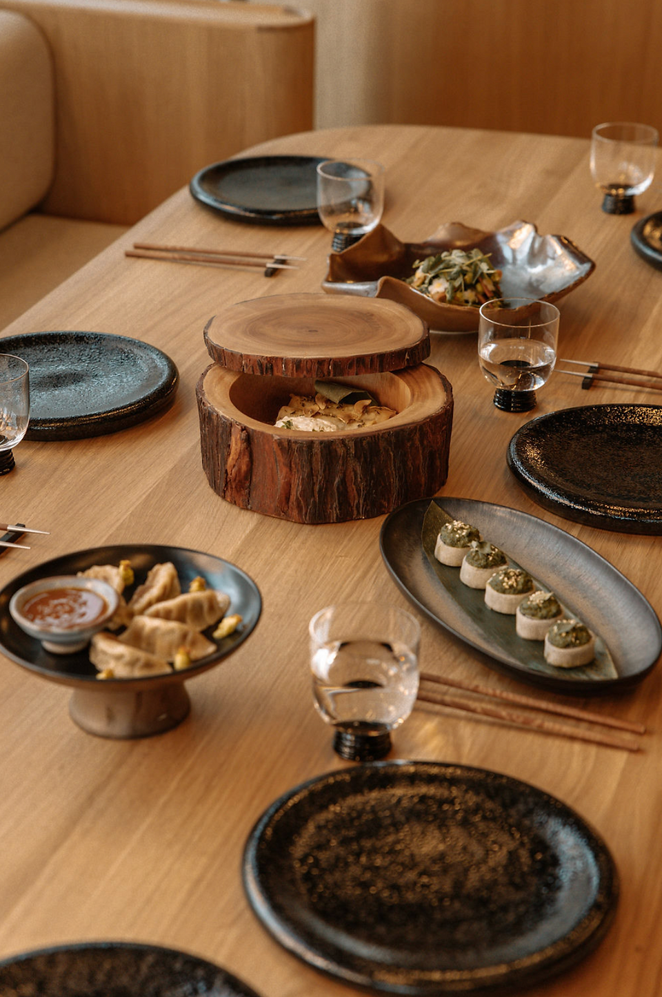 Table setting with Asian food, plates, glasses and chop sticks on display.