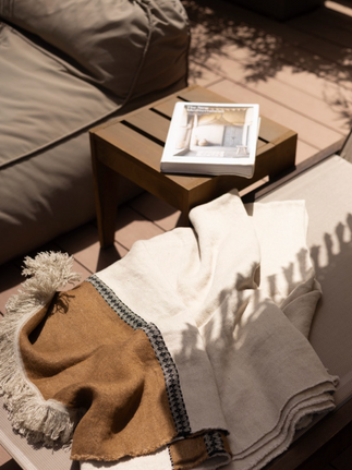 Blanket and book on outdoor furniture, sunlight casts shadows, interior design scene