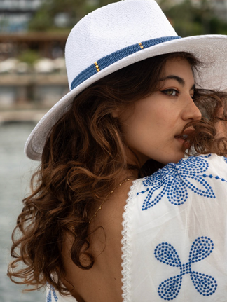 Woman wearing a white hat with blue trim, looking over her shoulder, smiling