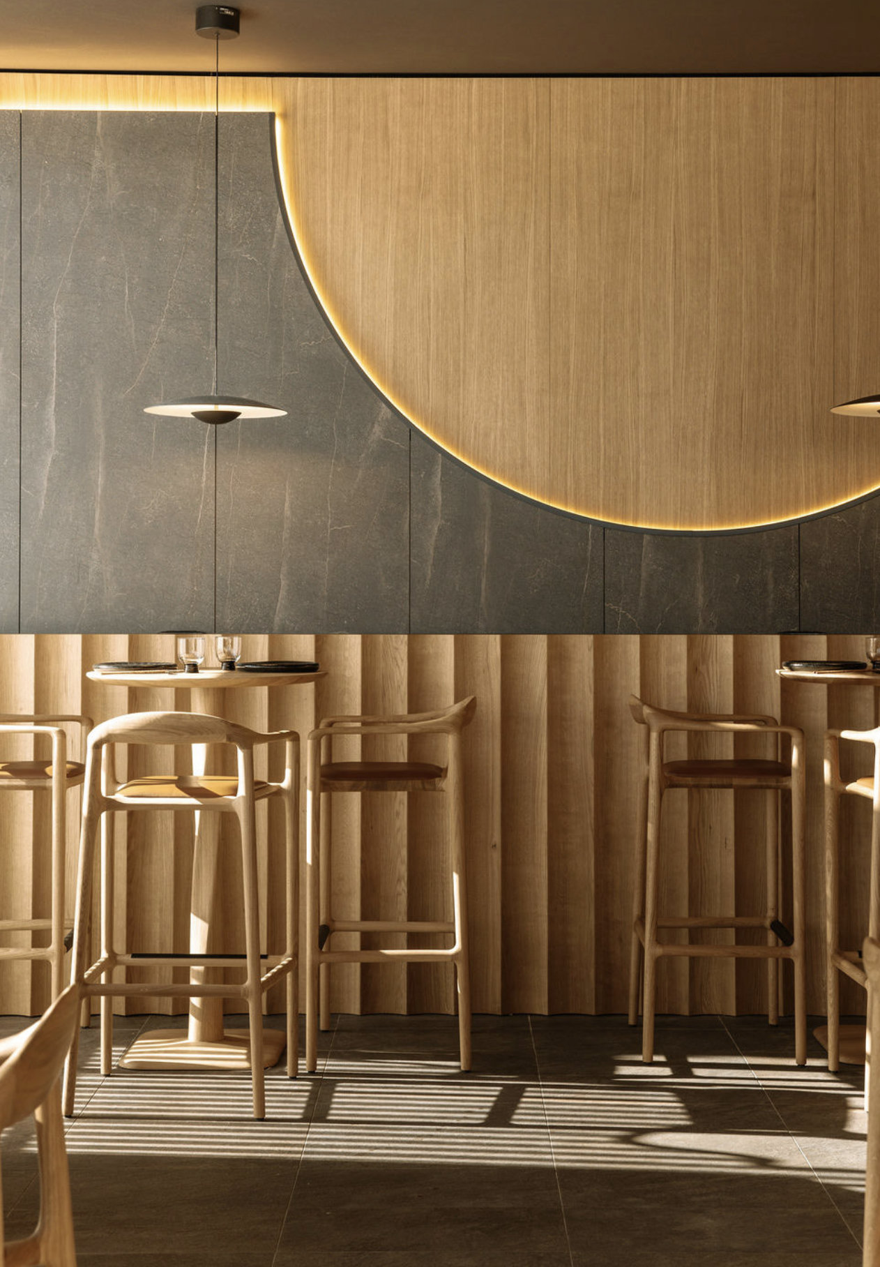 Wooden chairs and table inside a modern restaurant with decorative paneling.