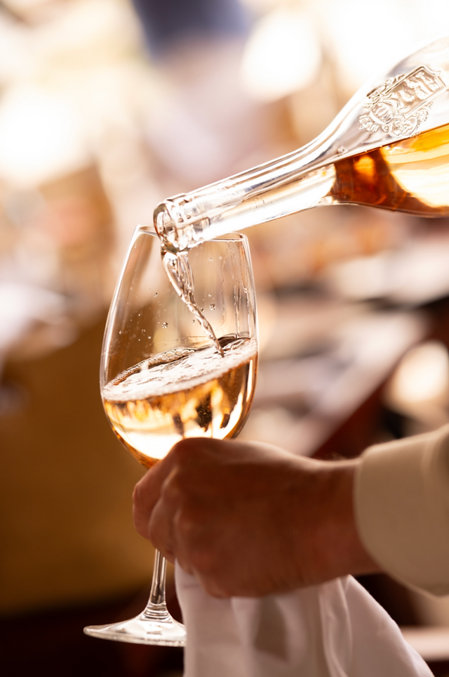 Pouring wine into a glass, close up shot with a hand holding it