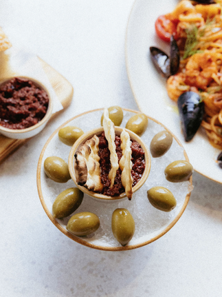 Close-up of olives around a bowl of tapenade and other food