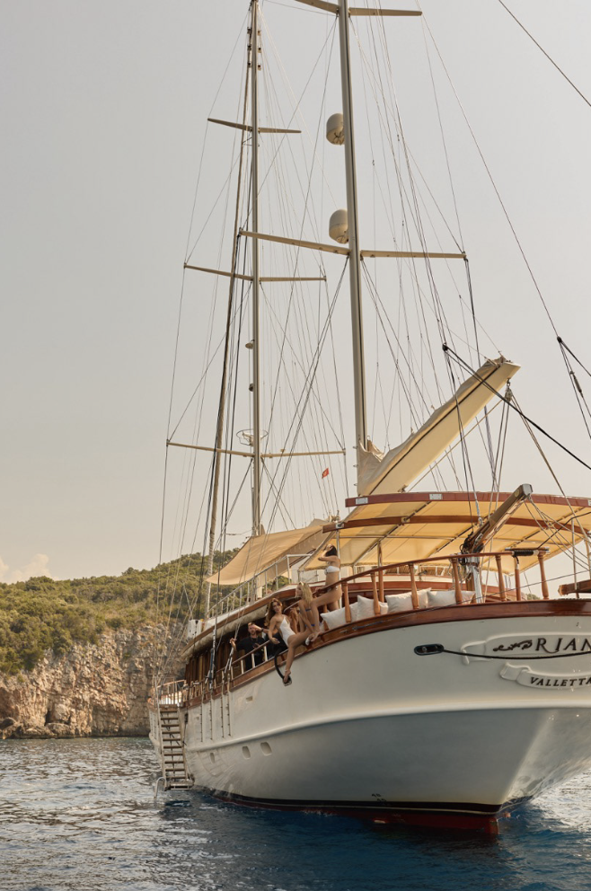 White sailboat sailing on the ocean with passengers against the sky