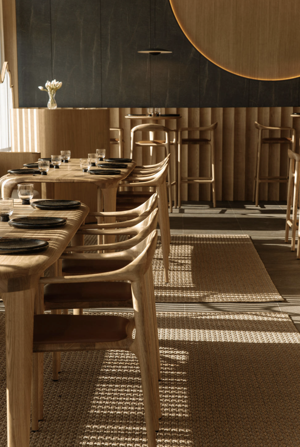 Wooden tables and chairs inside a modern restaurant with decorative details.