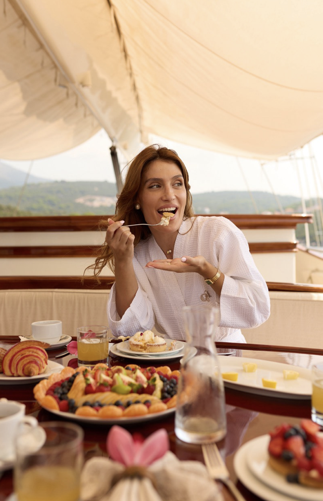 Woman enjoying fruit and pastries at a table; jelena zecevic on a yacht