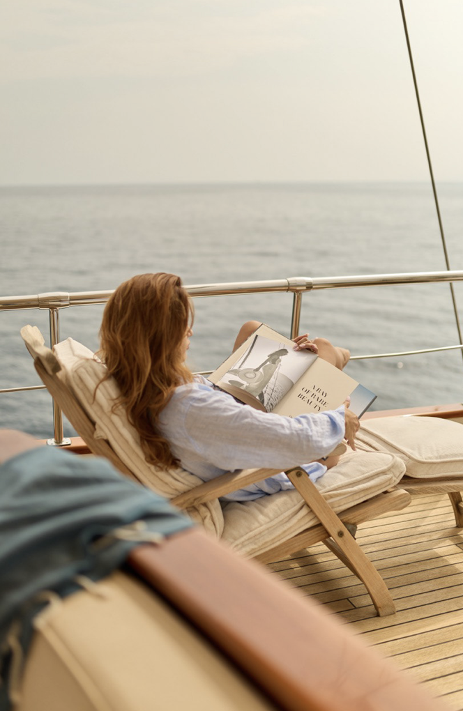 Woman relaxing and reading on a boat with ocean view and book.