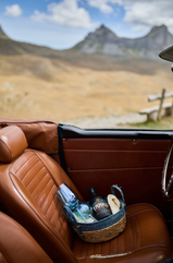 Classic car interior with wine and snacks overlooking a scenic landscape.